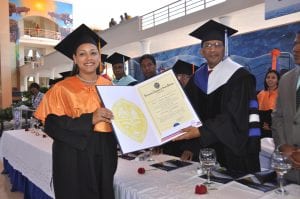 El Vicerrector de Extensión, maestro Rafael Nino Féliz, entrega el certificado a Yohanna Miguelina Herrera Méndez, investida de licenciada en Contabilidad, por obtener la más alta calificación, 90.9, Magna Cum Laude