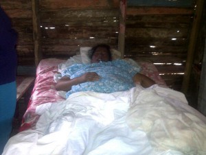 María Almida Aracena en el lecho de su cama, mientras sus familiares y vecinos esperan que dé señales de vida. Foto José Disla.